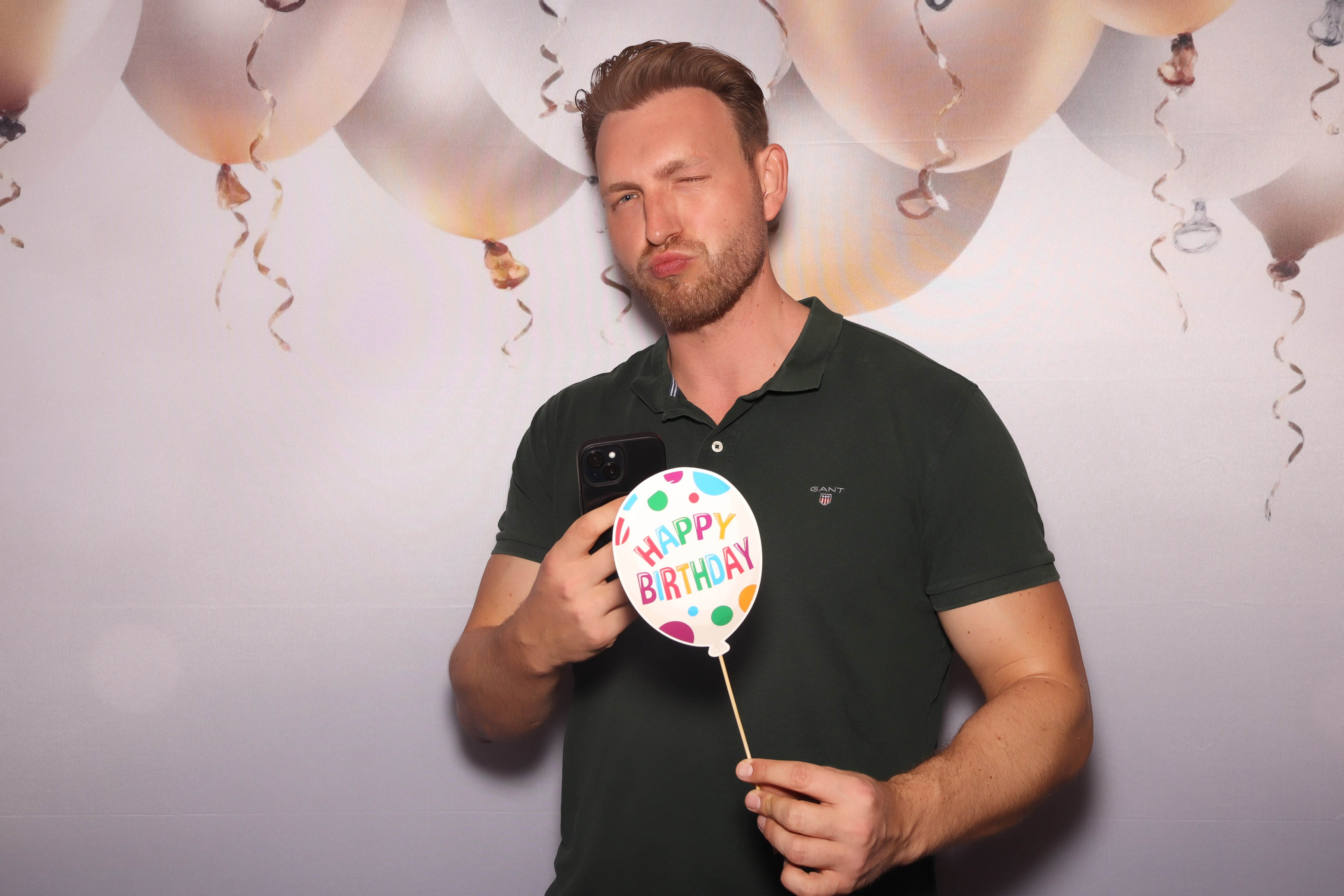 Gast an der Fotobox mit professionellem Ballon-Hintergrund und Happy Birthday Requisit